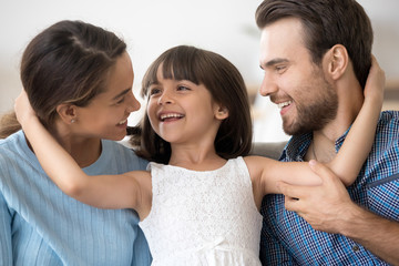Portrait of multi-ethnic attractive mother father adorable little preschool daughter sitting...