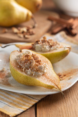 Half pears with cottage cheese, nuts and cinnamon on white dish.