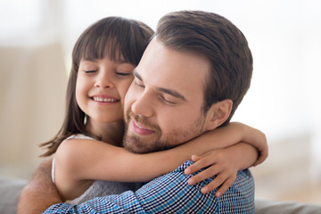 Portrait smiling loving handsome Caucasian father and adorable preschool daughter indoors. Daddy...