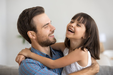Head shot portrait father and adorable preschool daughter have fun smiling and laughing spending free time on weekend at home together. Sincere emotions friendly multi-ethnic wellbeing family concept