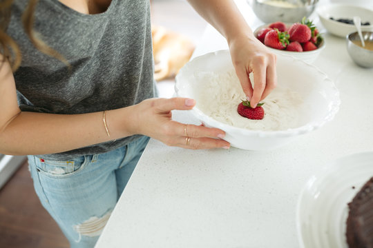 Woman dipping strawberries into whipped cream