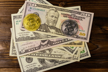 Golden and silver bitcoins and dollar bills on wooden desk