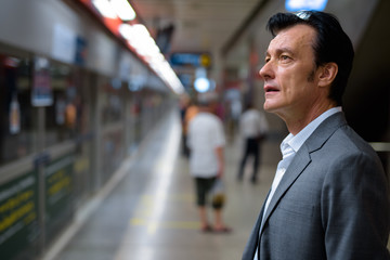 Fototapeta na wymiar Portrait of mature handsome businessman in train station