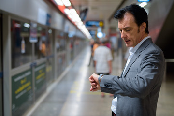 Portrait of mature handsome businessman checking time from watch