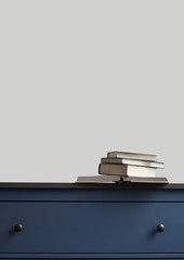 stack of books on blue chest of drawers