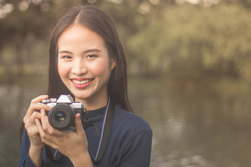 pretty cool young Asian woman with retro film camera or mirrorless camera in modern garden park