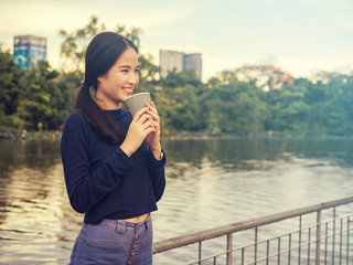 Beautiful women have enjoyed in the garden with coffee.Asian women drinking coffee.Asian girls like to drink coffee. Beautiful Asian girl inhale the smell of coffee.