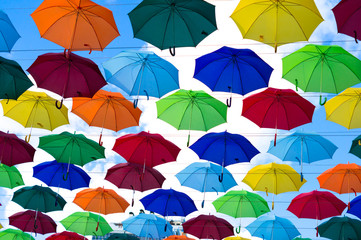 Fototapeta na wymiar many bright umbrellas hanged between buildings