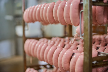 Raw sausages on racks in storage room at meat processing factory