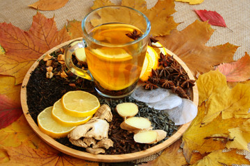 Warming autumn tea, various types of tea and spices on a tray, next to autumn leaves