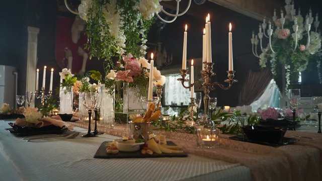 a table set with black arrows with food, wine glasses, flower vases, candlesticks with candles