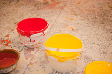 rote und gelbe Farbeimer auf dem Boden in einem Atelier