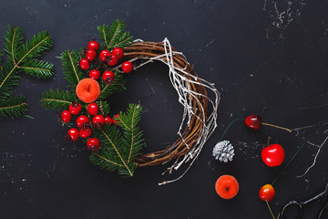 Making Christmas wreath. Rustic Christmas grapevine wreath supplies on dark, rustic wooden background. Top view, blank space