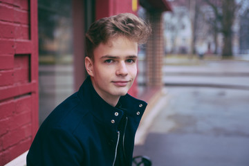 portrait of elegant teenager, young man in a blue coat 