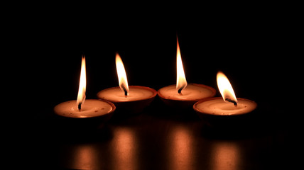 Four butter lamp candles glowing in the dark, mainly used during Diwali or Deepawali festival