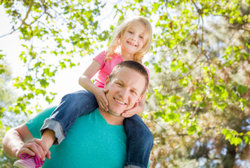 Fototapeta premium Cute Young Girl Rides Piggyback On Her Dads Shoulders