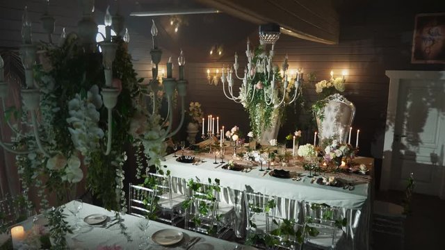a table set with black arrows with food, wine glasses, flower vases, candlesticks with candles behind which stands two thrones