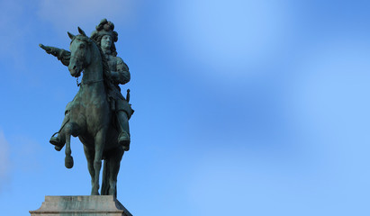 Statue of Louis 14 on the background of blue sky.