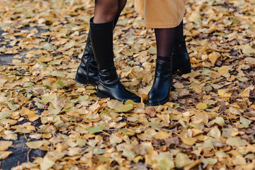 woman foot among yellow leafs at autumn colorful park