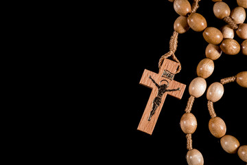 A brown rosary lying on a black background