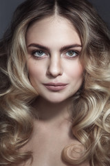 Fototapeta premium Young beautiful blonde woman with long curly hair