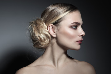 Profile portrait of young beautiful woman with fancy messy hair bun