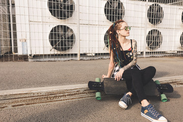 young girl with tattoo and dreadlocks on urban industrial background