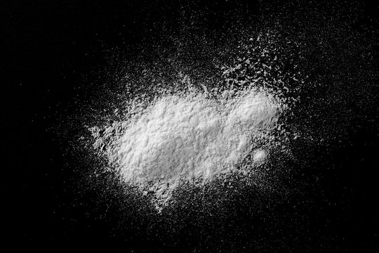 Pile of wheat flour isolated on black background, powder texture, top view with clipping path