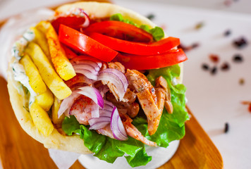 greek lamb meat gyros with tzatziki sauce, vegetables, feta cheese and french fries