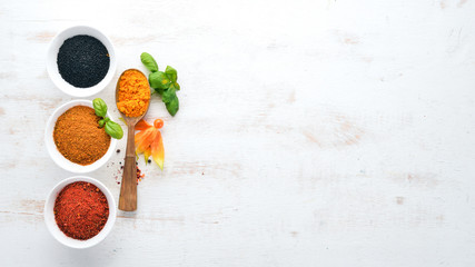 A set of Spices and herbs on a white wooden table. Basil, pepper, saffron, spices. Indian traditional cuisine. Top view. Free copy space.