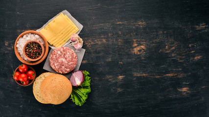 Raw burger Cooking a burger with meat. On a black wooden background. Top view. Free copy space.