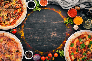 A set of Italian pizza. Italian cuisine. On a black wooden background. Free copy space. Top view.