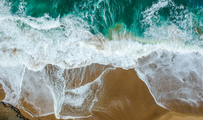 Aerial view of sandy beach with waves and clear ocean water. Drone photo 