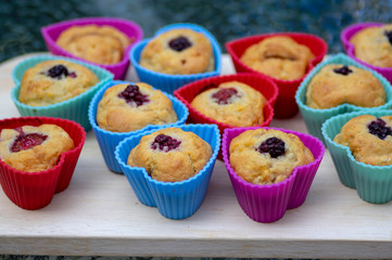 Banana muffins with chocolate, blackberries, strawberries, nuts and raisins in silicone molds on wooden mat, colorful hearts