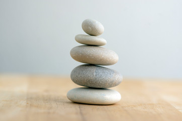 Obraz na płótnie Canvas Stone cairn on striped grey white background, five stones tower, simple poise stones, simplicity harmony and balance, rock zen