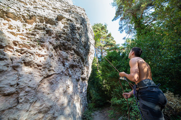 Fototapeta premium From below of man with rope on rock looking up checking another climber before going up 