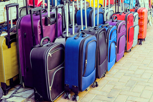 Cheap luggage in the street shop. Multicolored travel suitcases. toning