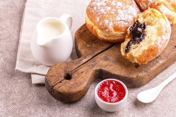 Tasty sweet sugary chocolate donuts with raspberry jam and milk