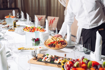 Waiter serving table in the restaurant preparing to receive guests.