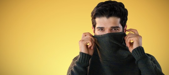 Fototapeta premium Composite image of portrait of man hiding face with sweater