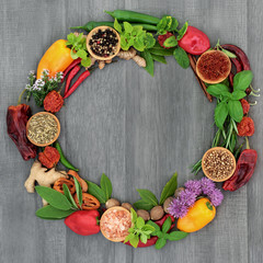 Herb and spice wreath with a selection of dried and fresh herbs and flowers on rustic wood background.