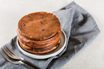Stack of homemade chocolate pancakes with blueberries and chocol