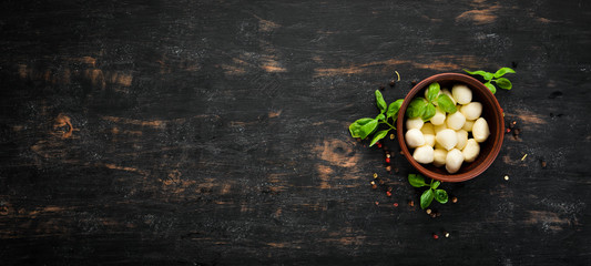 Mozzarella cheese in a clay plate. Top view. On a wooden background. Free copy space.