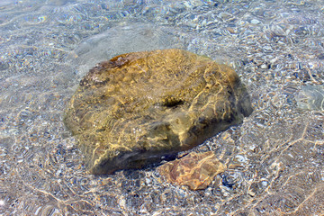 Dark yellow rock boulder in the sea water horizontal center