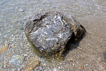 Grey rock boulder in the sea water center horizontal