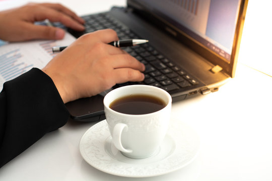 Businesswoman having coffee while using laptop at desk