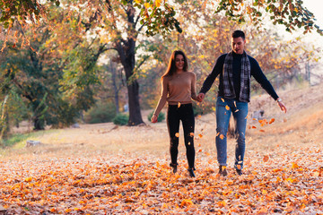 Couple kicking leaves feeling happy and joyful.