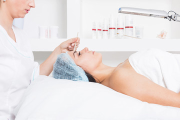 A patient woman with closed eyes lies in the doctor's office. Cosmetic procedures in cosmetology office. Face of the patient close-up