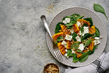 Autumn pumpkin  salad with spinach, feta cheese and walnuts.Top view with copy space.