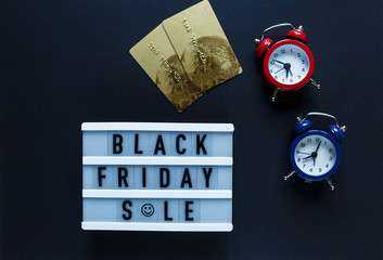 Creative flat lay composition sale text on lightbox, credit cards, red, blue clock on black background with copy space. Template Cyber Monday, Black Friday sale mockup 